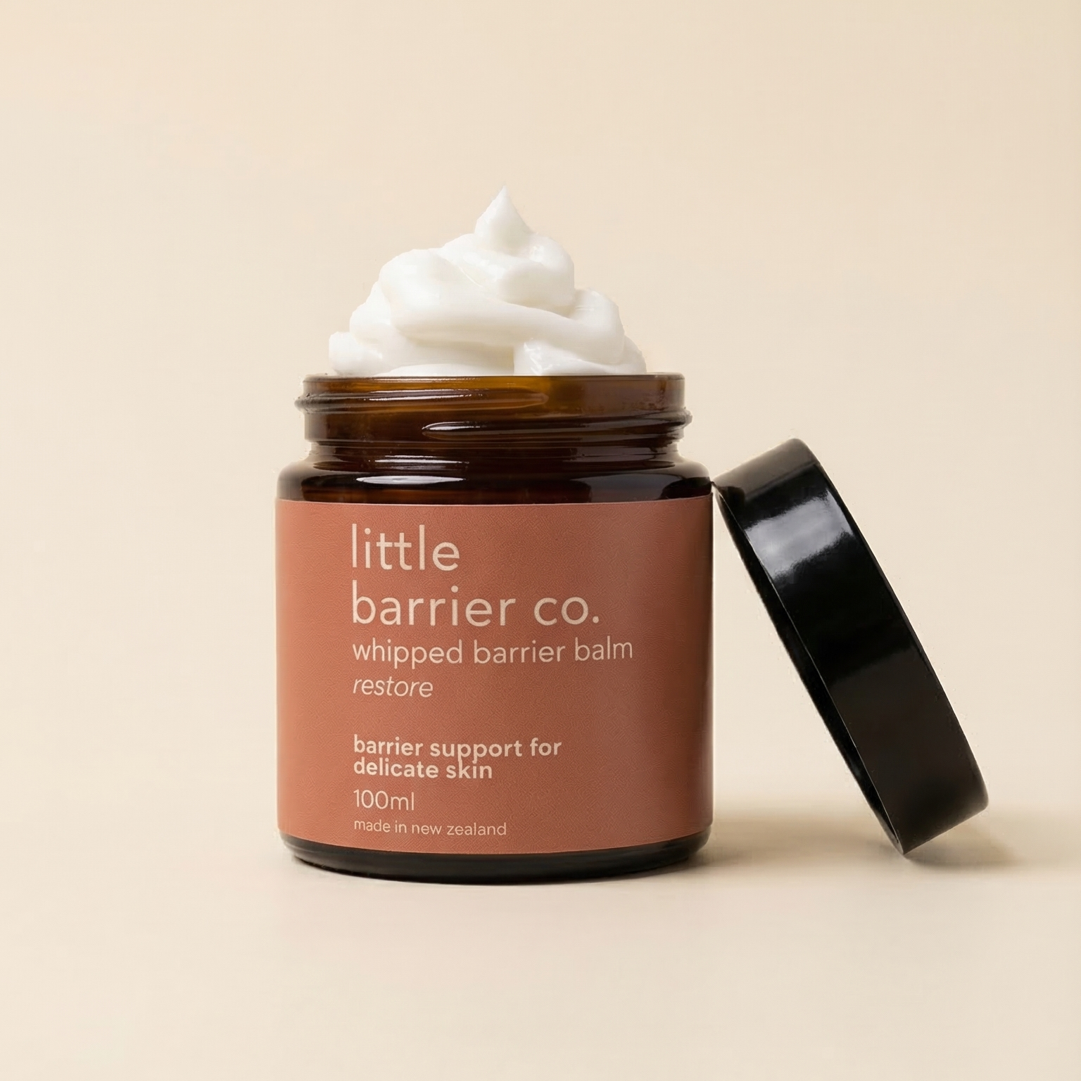 Jar of 'little barrier co.' whipped barrier balm with a beige background
